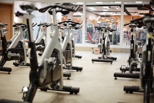 Several fitness bicycles for visitors of leisure center and instructor in gym