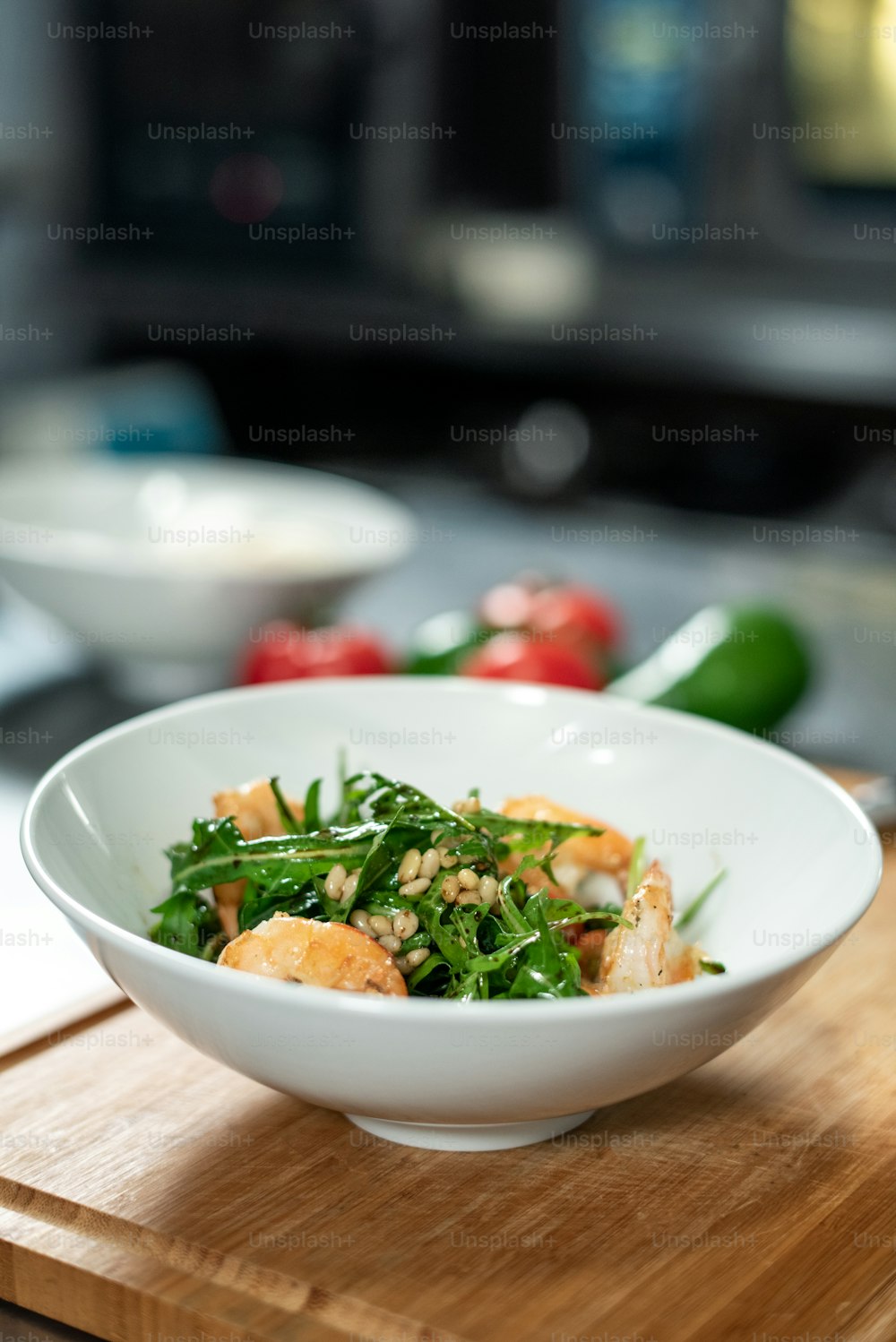 Holzbrett mit weißer Keramikschüssel mit appetitlichem Salat bestehend aus Ruccola, gekochten Garnelen und anderen Zutaten mit Öl