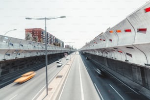 스페인 바르셀로나 중심부의 소실점으로 뻗어있는 현대적인 고속도로, 콘크리트 방음 벽, 긴 노출, 여러 개의 움직임이 흐릿한 자동차와 버스, 화창한 여름날