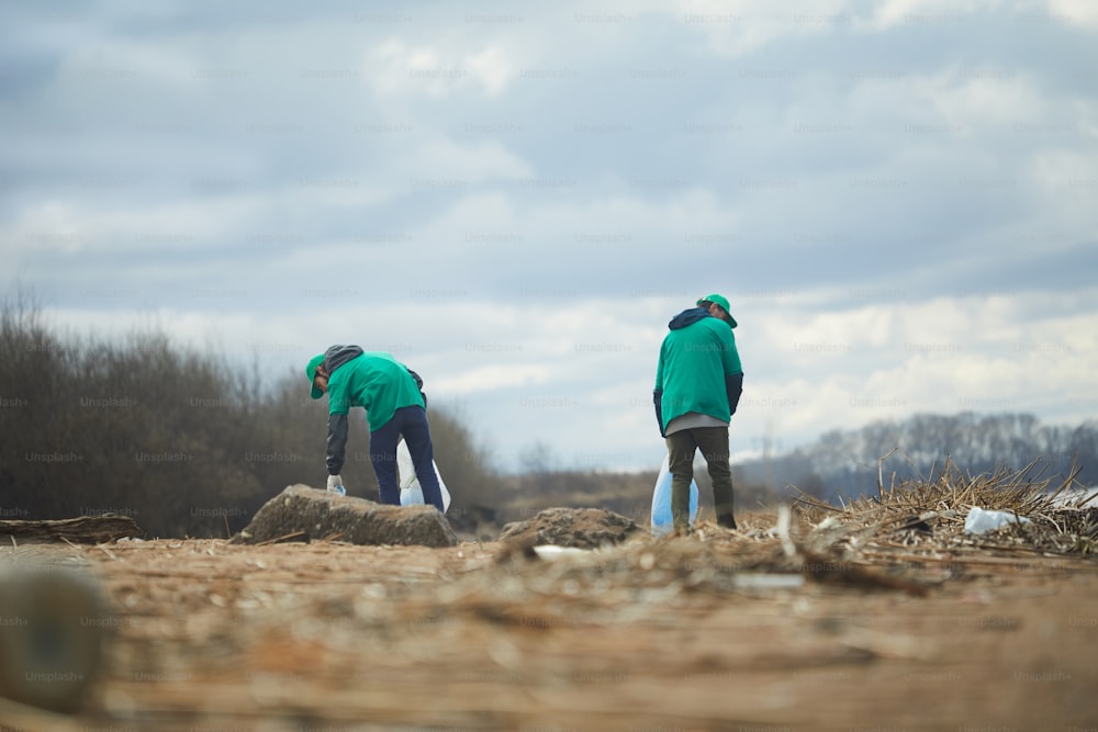 Two active greenpeacers working on littered abandoned territory somewhere in the outskirts