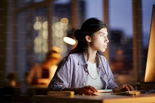 Junge Geschäftsfrau bei der Arbeit am Computer in der Nachtschicht