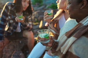 Gruppe junger Menschen, die kalte Getränke genießen, während sie während einer schönen multiethnischen Party Zeit miteinander verbringen.