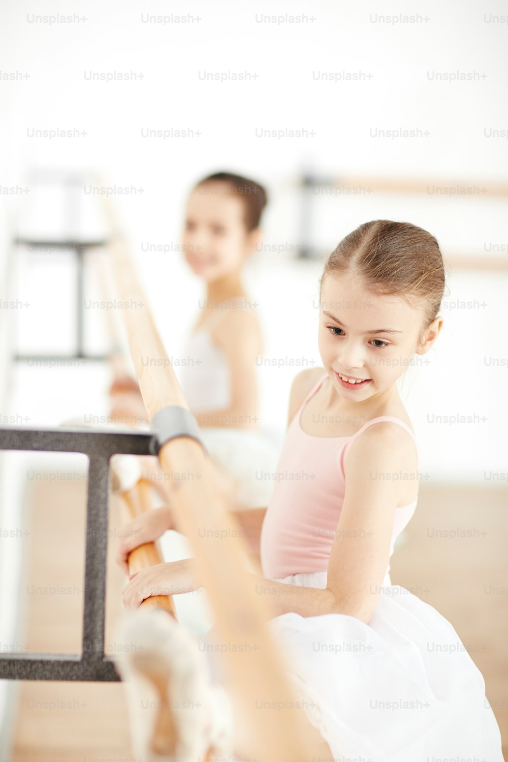 배경에 친구와 함께 흰색 스튜디오에서 춤을 연습하는 젊은 발레리나