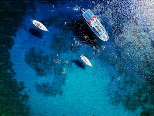 Foto aérea da bela lagoa azul no dia quente de verão com barco à vela. Vista superior das pessoas estão nadando ao redor do barco.