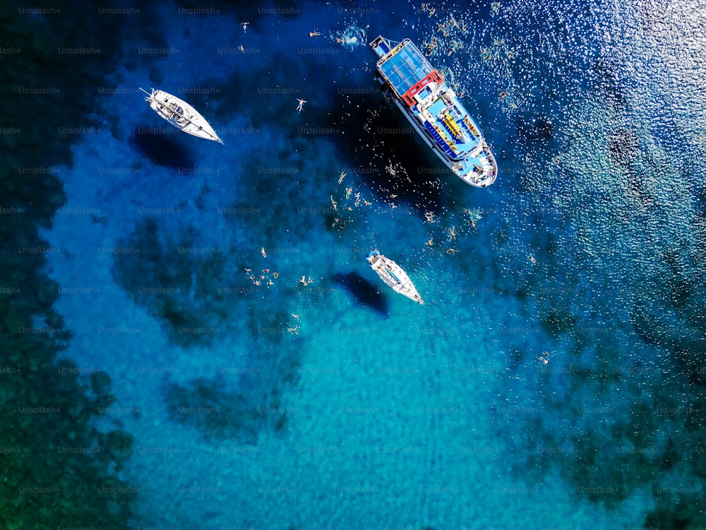 Ripresa aerea della bellissima laguna blu nella calda giornata estiva con barca a vela. Vista dall'alto delle persone che nuotano intorno alla barca.