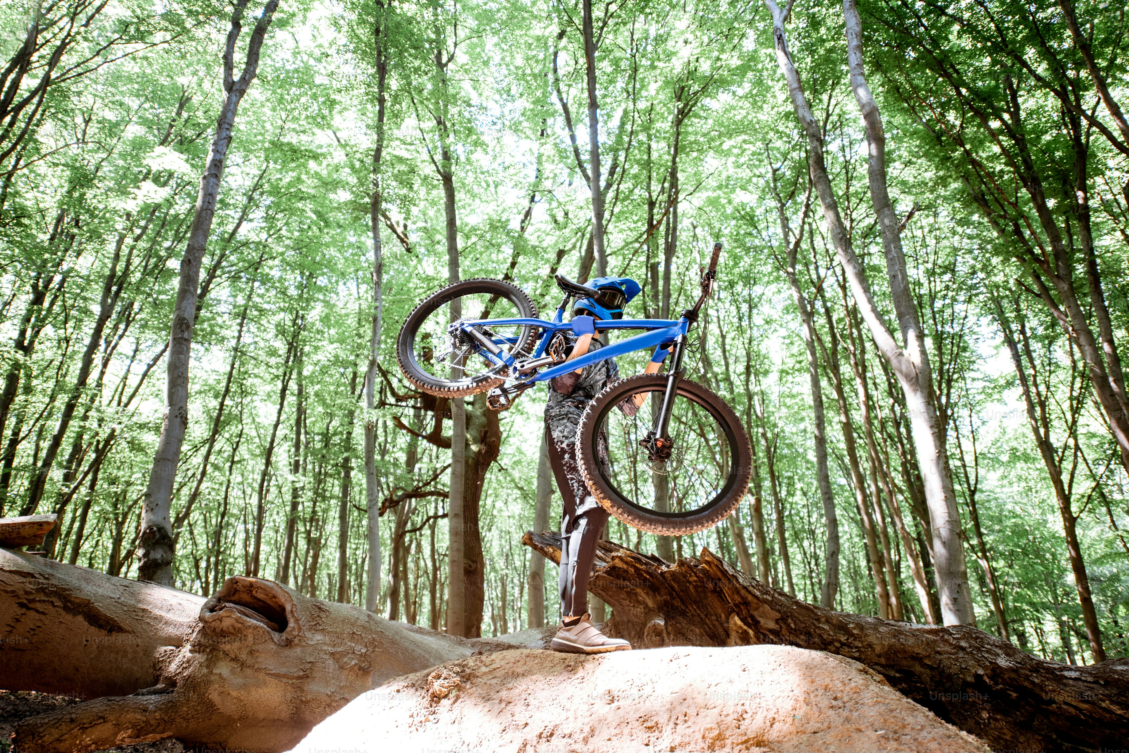 Ciclista professionista che trasporta la bicicletta mentre pedala fuori strada nella foresta