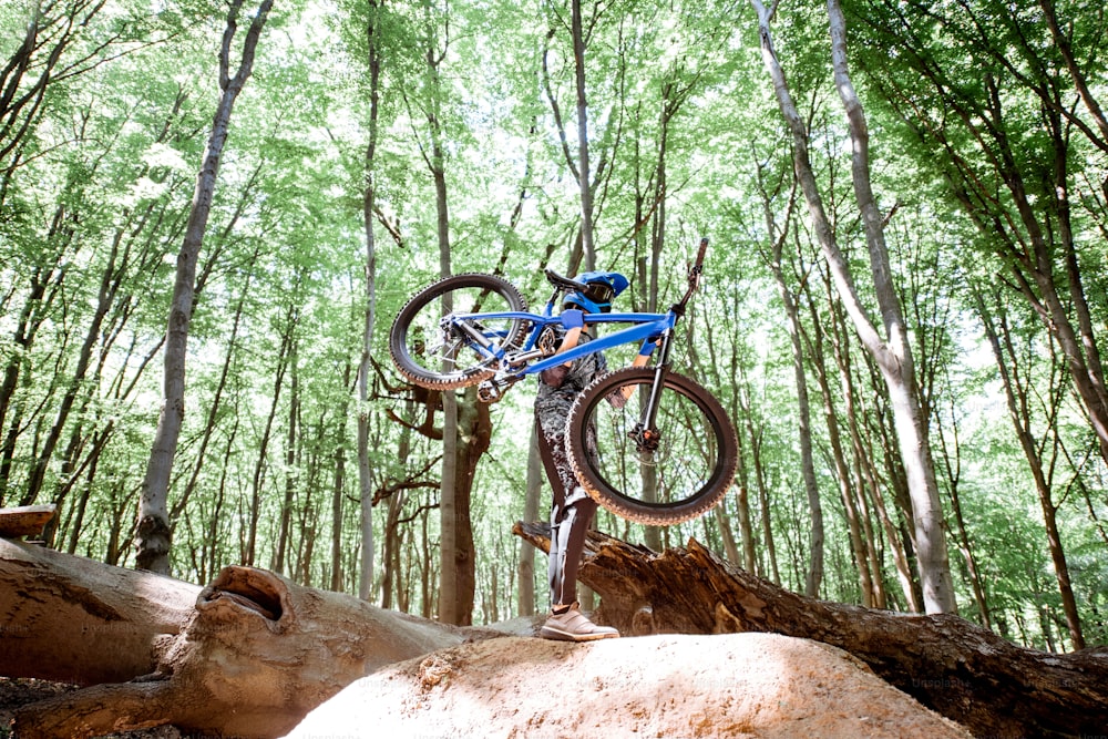 Professional cyclist carrying bicycle while riding off road in the forest