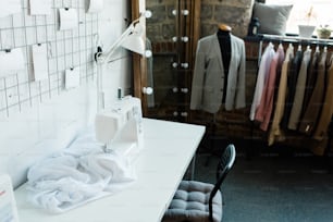 Parte del taller contemporáneo del diseñador de moda con raqueta y espejo por esquina y máquina de coser eléctrica en el escritorio