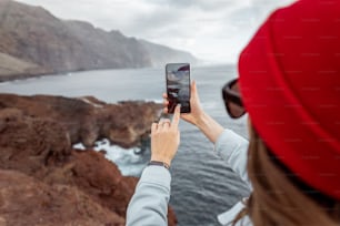 Femme voyageuse photographiant au téléphone des vues à couper le souffle sur la côte rocheuse de l’océan lors d’un voyage sur l’île de Tenerife, Espagne