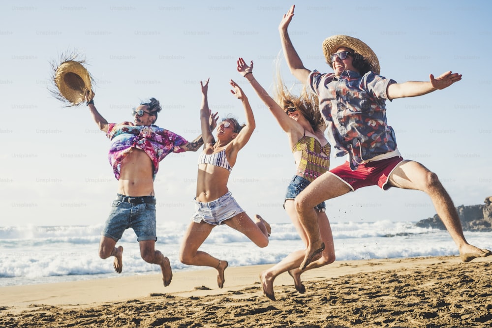 Happiness and youthful generation people have fun together in friendship at the beach for summer holiday vacation jumping like crazy and laughing a lot with blue sea and sky in background