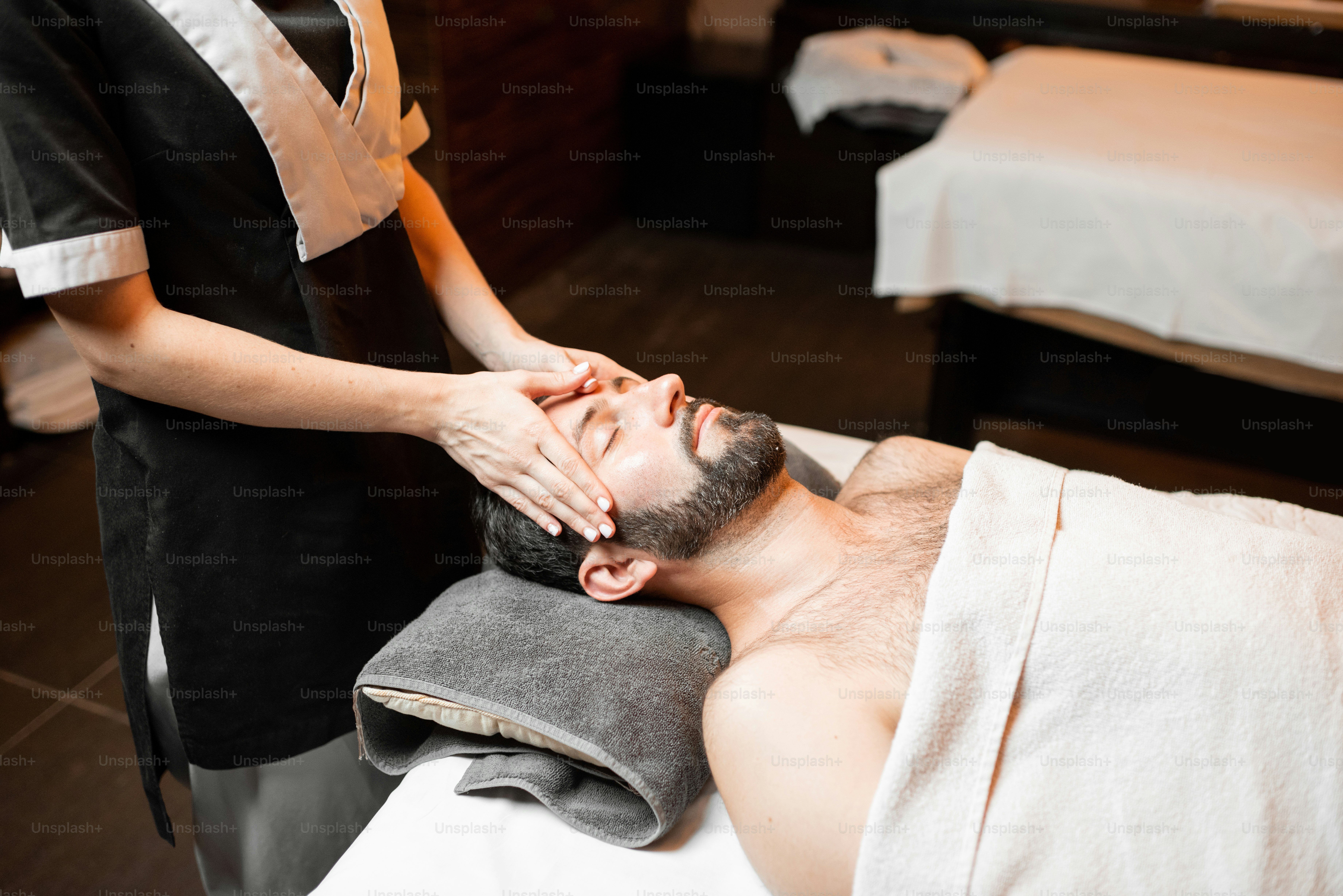 Pria berjanggut menerima pijatan wajah, bersantai di salon Spa, close-up