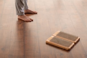 Young active barefoot man in sportspants standing on wooden floor by yoga therapy pads with metallic bristles during training