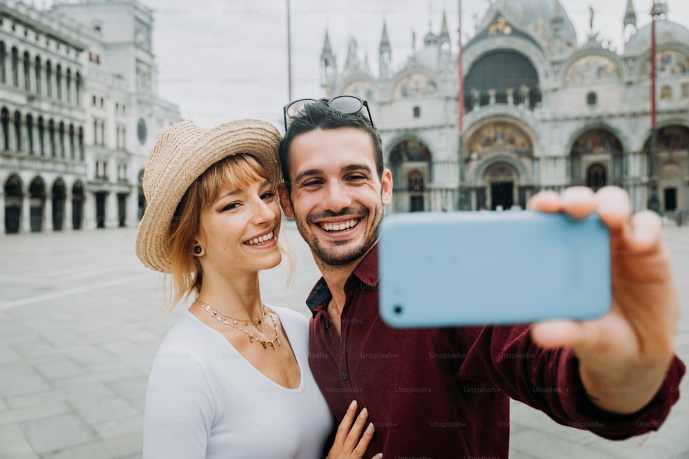 Young couple of lovers taking a selfie portrait at Piazza San Marco in Venice, Italy. Loving people are kissing outdoor. Vintage filter