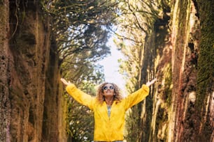 Viagem e felicidade pessoas conceito de estilo de vida livre com jovem alegre e bela mulher adulta desfrutando da floresta e da natureza ao redor com jaqueta amarela
