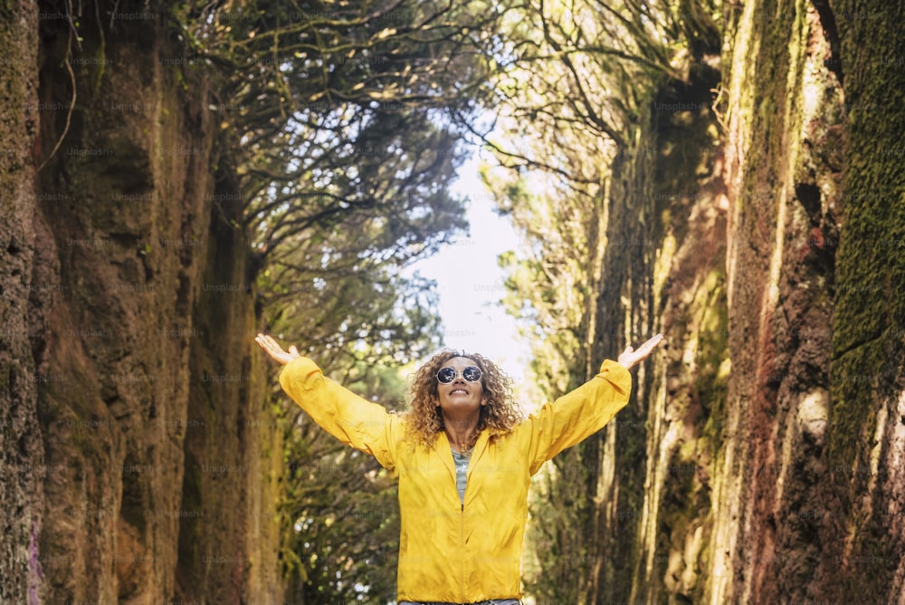 黄色いジャケットで森と自然を楽しむ若い陽気で美しい大人の女性と、旅行と幸福の人々の自由なライフスタイルのコンセプト