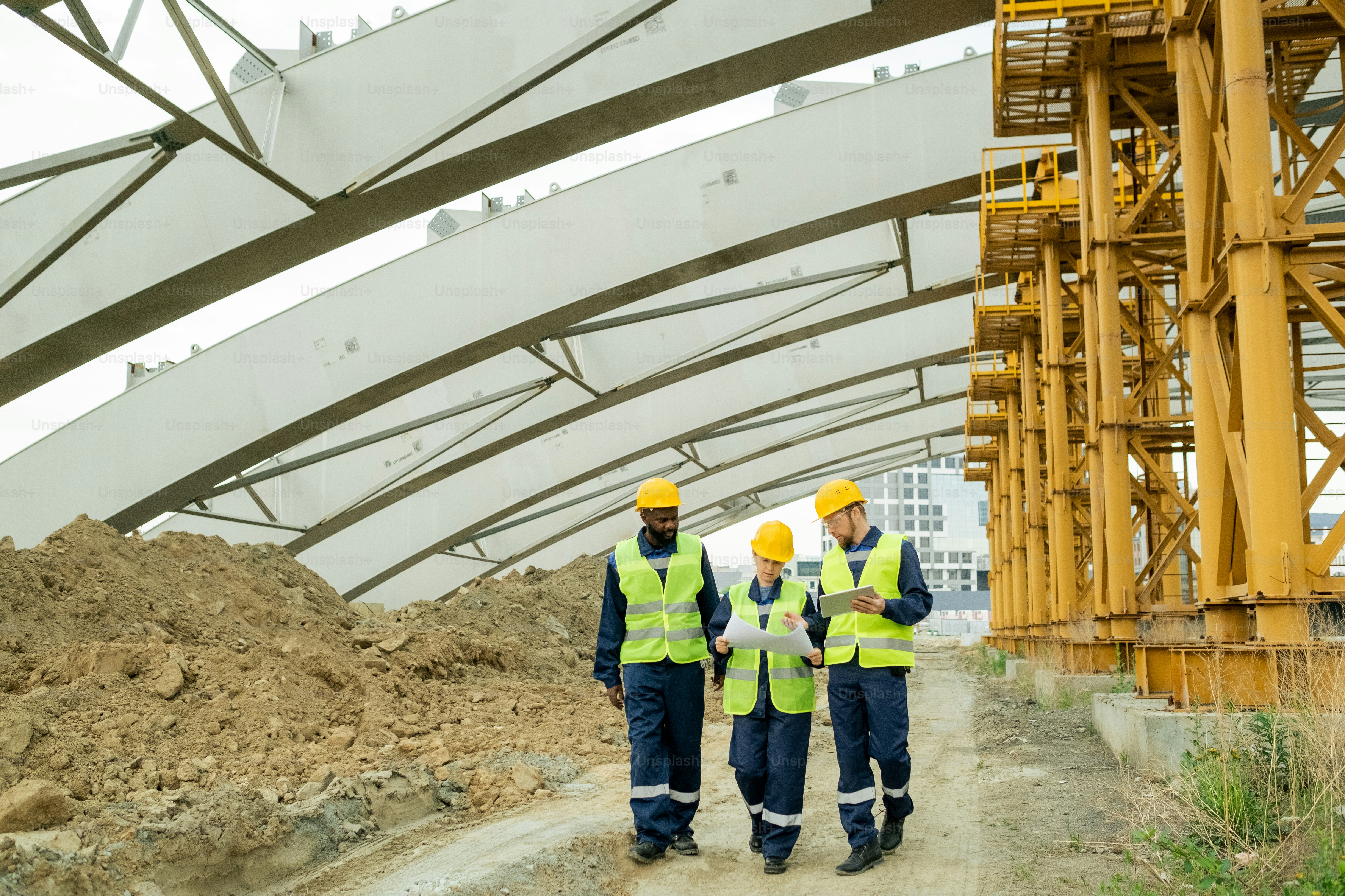 Contemporary engineers discussing working document while moving along construction site