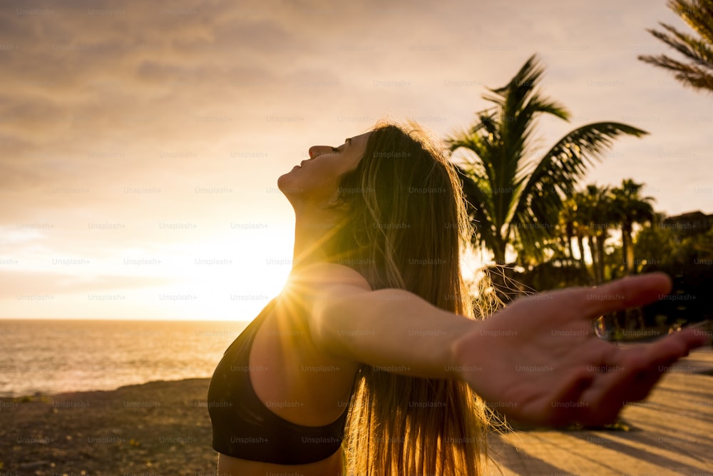 Stile di vita di persone sane che si godono il tramonto e l'attività di fitness da soli - bella donna sentire il sole e l'oceano ossigeno dopo l'allenamento lezione di sessione sportiva - braccia aperte e libertà respirare