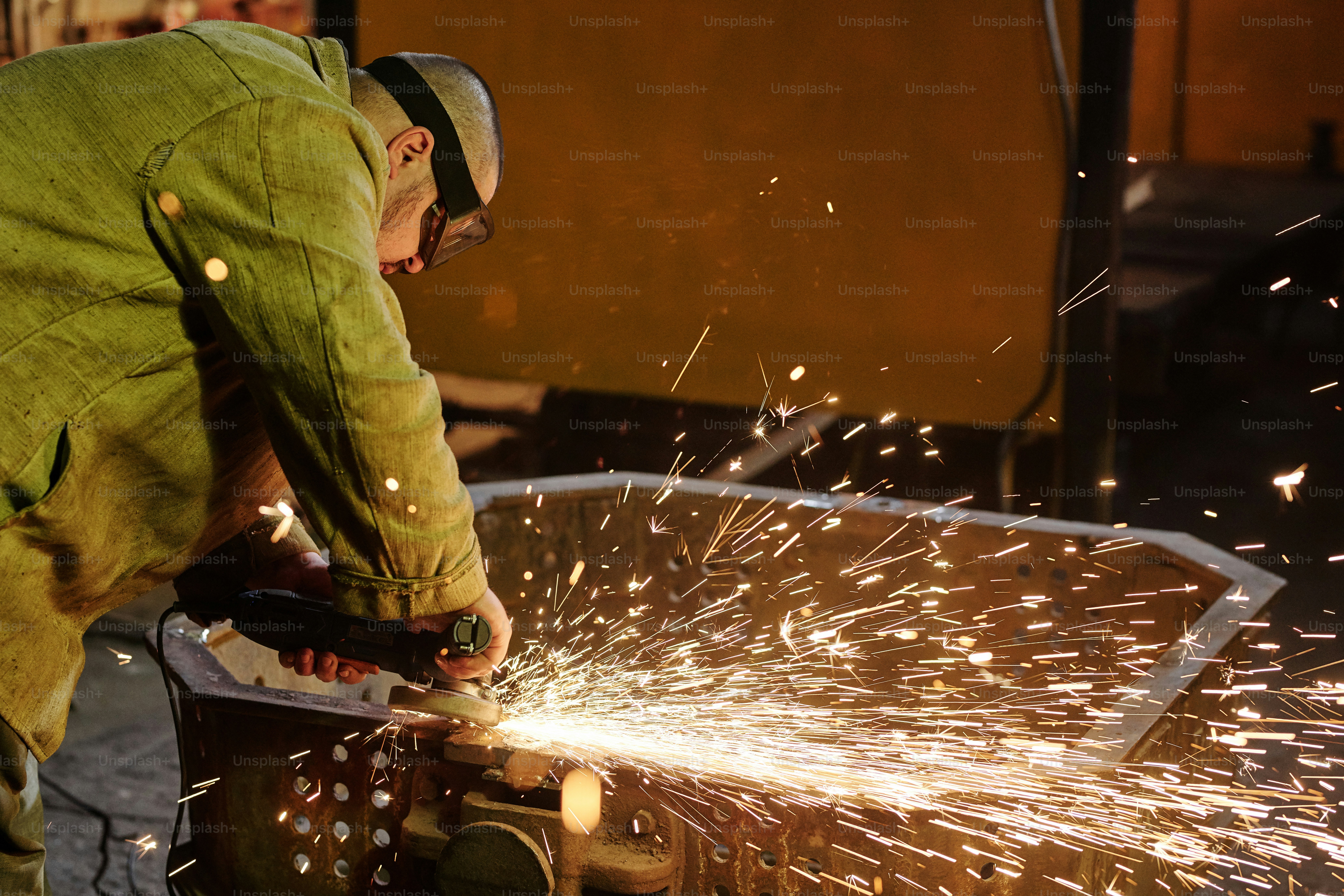 Manual worker in protective workwear working with steel welding in assembly workshop