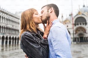 Hermosa pareja de enamorados en Venecia, Italia. Amantes románticos besándose en una cita en la Plaza de San Marcos, Venecia.