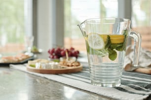 Primer plano de una jarra vidriosa de limonada en una servilleta pelada preparada para la cena en casa