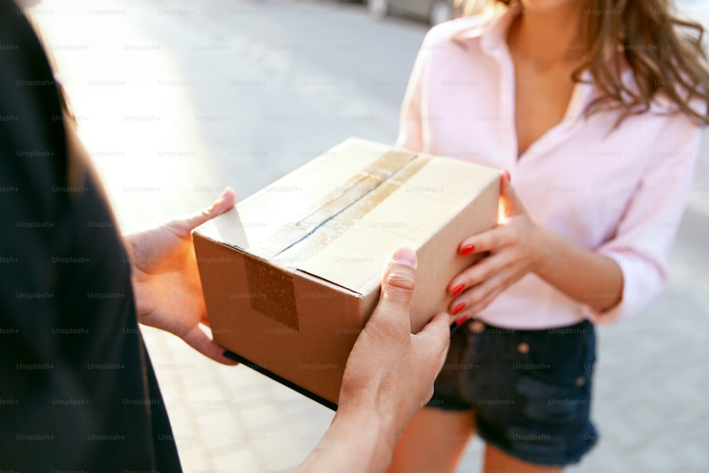 Courier Delivery Service. Closeup Of Woman's Hands Receiving Package From Delivery Man. High Resolution