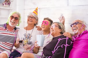 Grupo de alegres y felices caucásicos mezclados generaciones de generaciones desde abuelos hasta nietos divirtiéndose juntos celebrando una fiesta como cumpleaños. Concepto de carnaval en casa para la familia - todos riendo