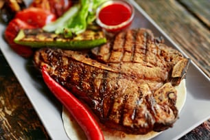 Grillfleisch mit Gemüse und Sauce auf der Tischnahaufnahme. Gebratenes Steak im Grill Restaurant. Hohe Auflösung