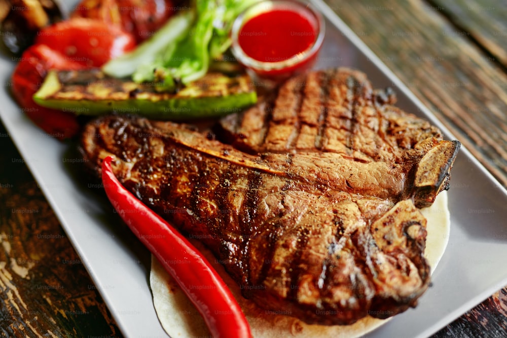 Barbecue Meat With Vegetables And Sauce On Table Closeup. Roasted Steak At Grill Restaurant. High Resolution