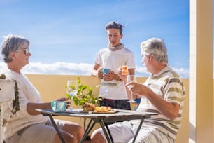 grandfathers adult mature and teenager grandson enjoy outdoor in the terrace some leisure with food and drinks. ocean and city view, vacation sunny day nice weather concept and background. happy people family together