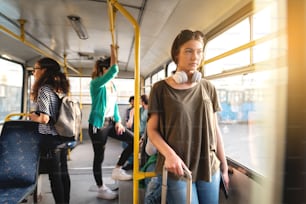 Caucasian girl looking through window and standing in public transport.