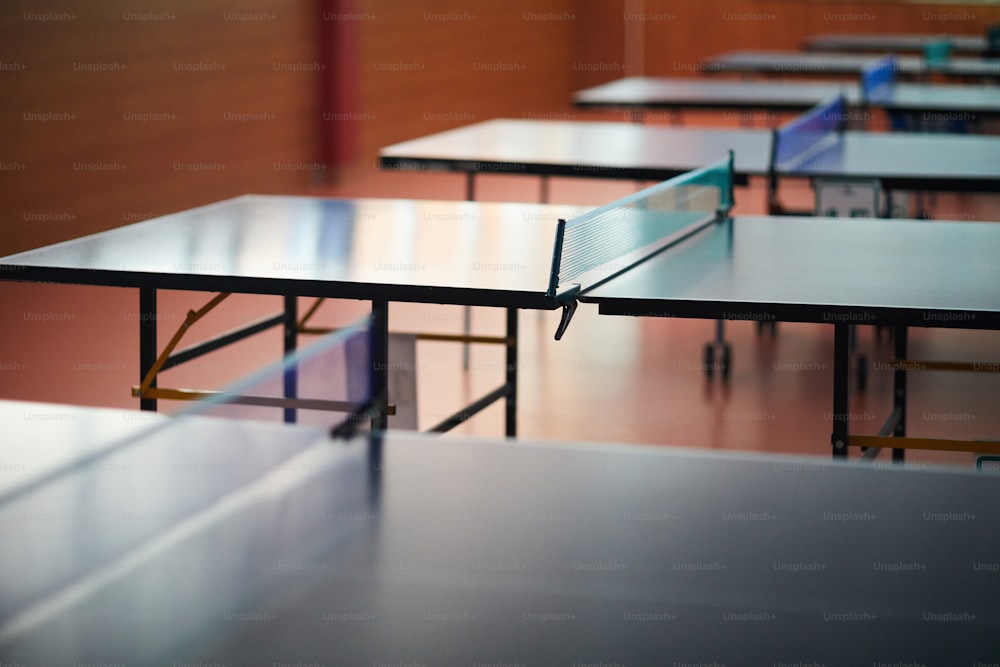 Mesa grande para jogar tênis com rede baixa no centro em sala vazia