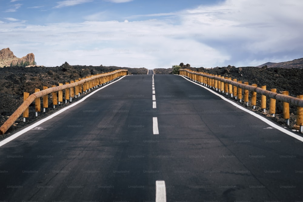 long way road of asphalt with white straight line in the middle and infinite direction and travel distance concept. asphalt and mountains around for traveler and adventure concept. no cars no people