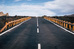 long way road of asphalt with white straight line in the middle and infinite direction and travel distance concept. asphalt and mountains around for traveler and adventure concept. no cars no people