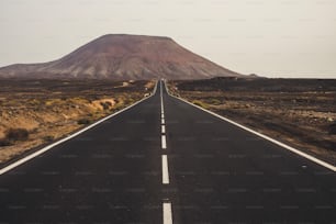 long way asphalt road in the middle of a mountains and valley peaks. white line to the infinite for travel and destination concept in alternative place of vacation