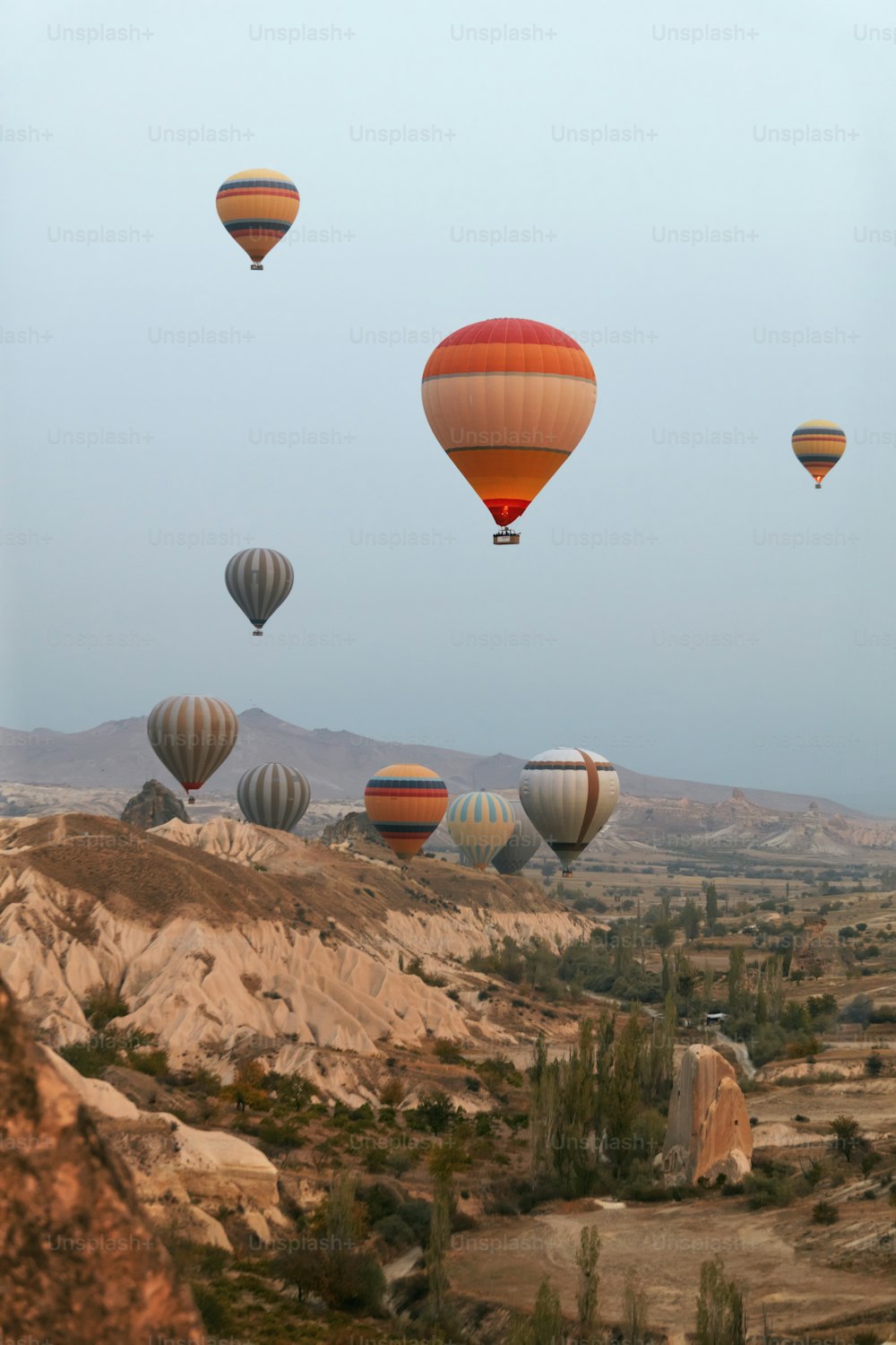 Hot Air Balloons In Sky. Colorful Flying Balloons In Nature Above Stone Hills. High Resolution
