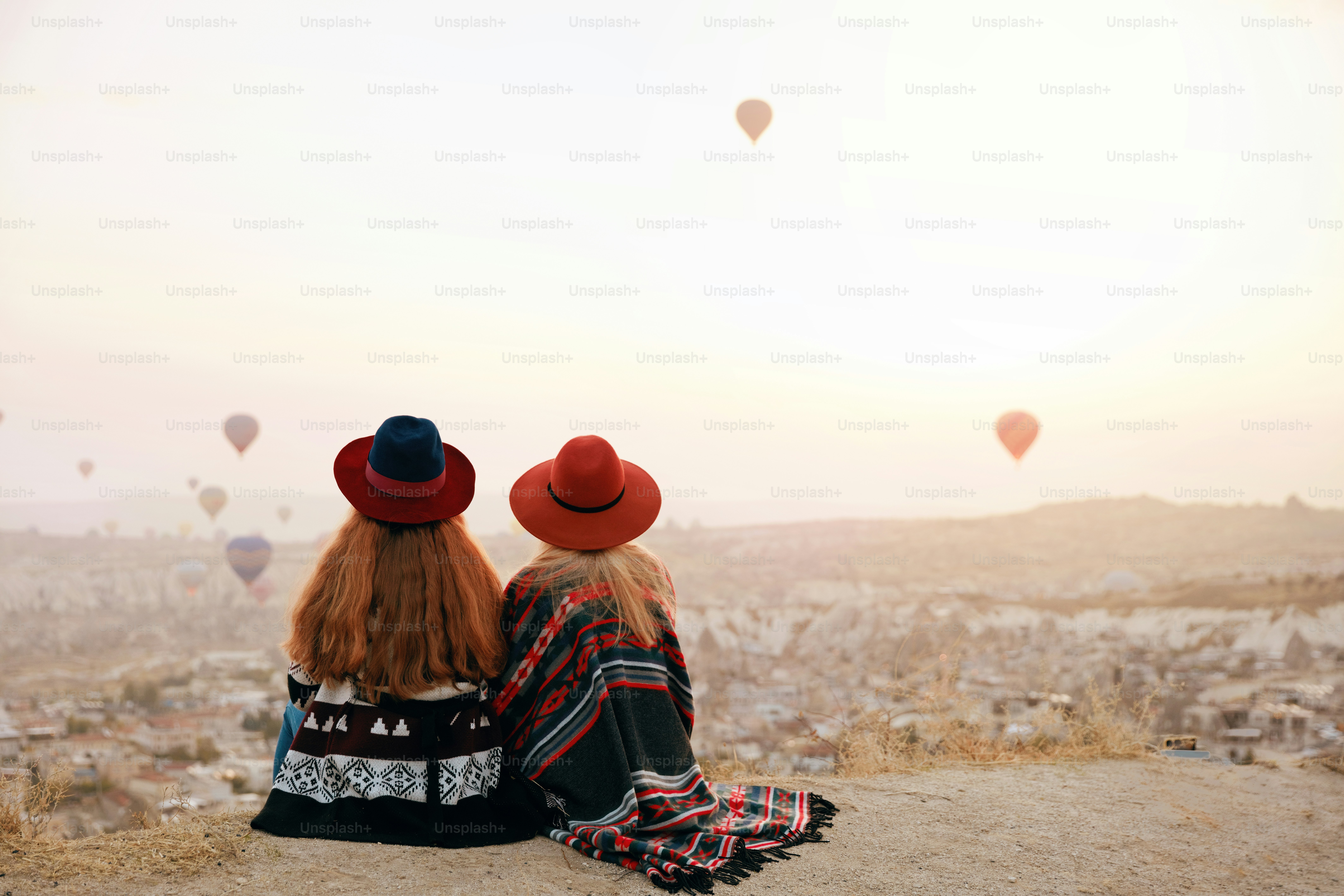 Le persone viaggiano. Donne in cappelli seduti sulla collina che godono di vista volanti mongolfiere in Cappadocia Turchia. Alta risoluzione