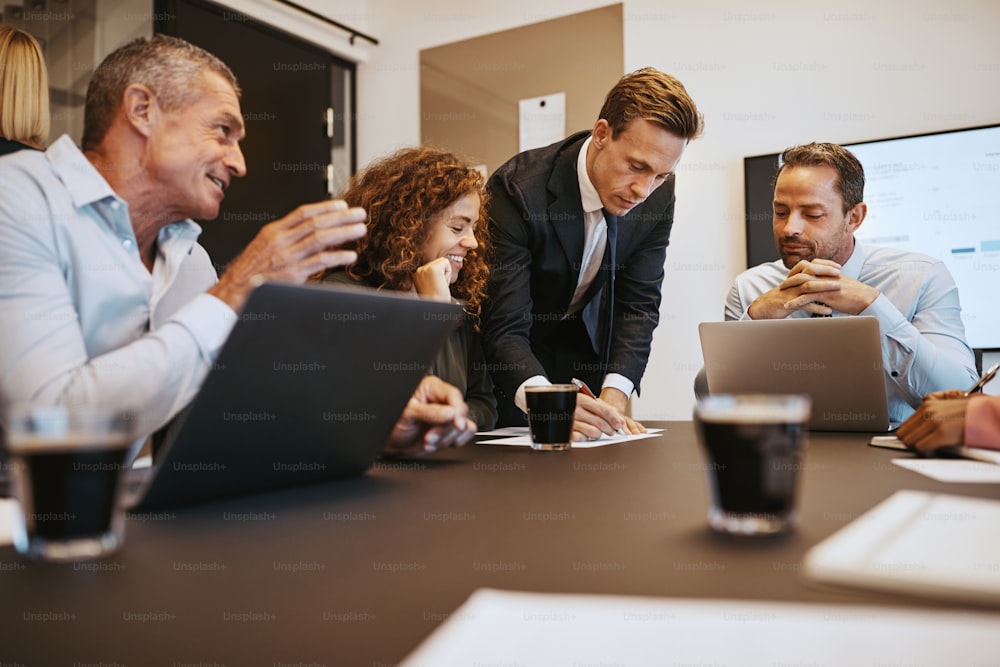 Grupo de empresários sorridentes conversando durante uma reunião em torno de uma mesa em uma sala de reuniões do escritório