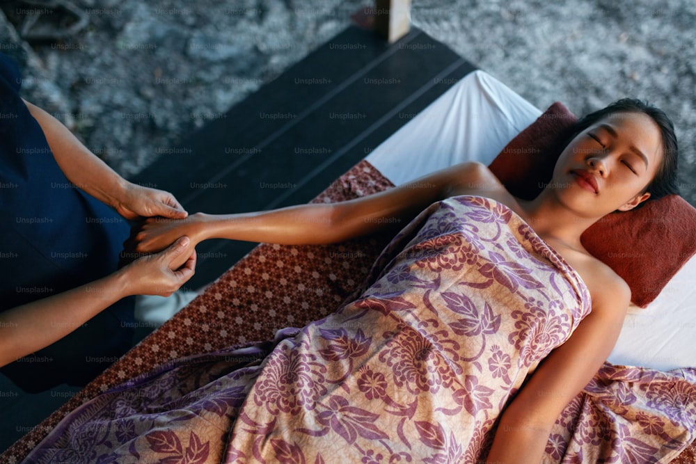 태국 바디 마사지. 아름다운 아시아 여성이 스파에서 손 마사지를 받고 리조트에서 휴식을 취하고 있습니다. 고해상도