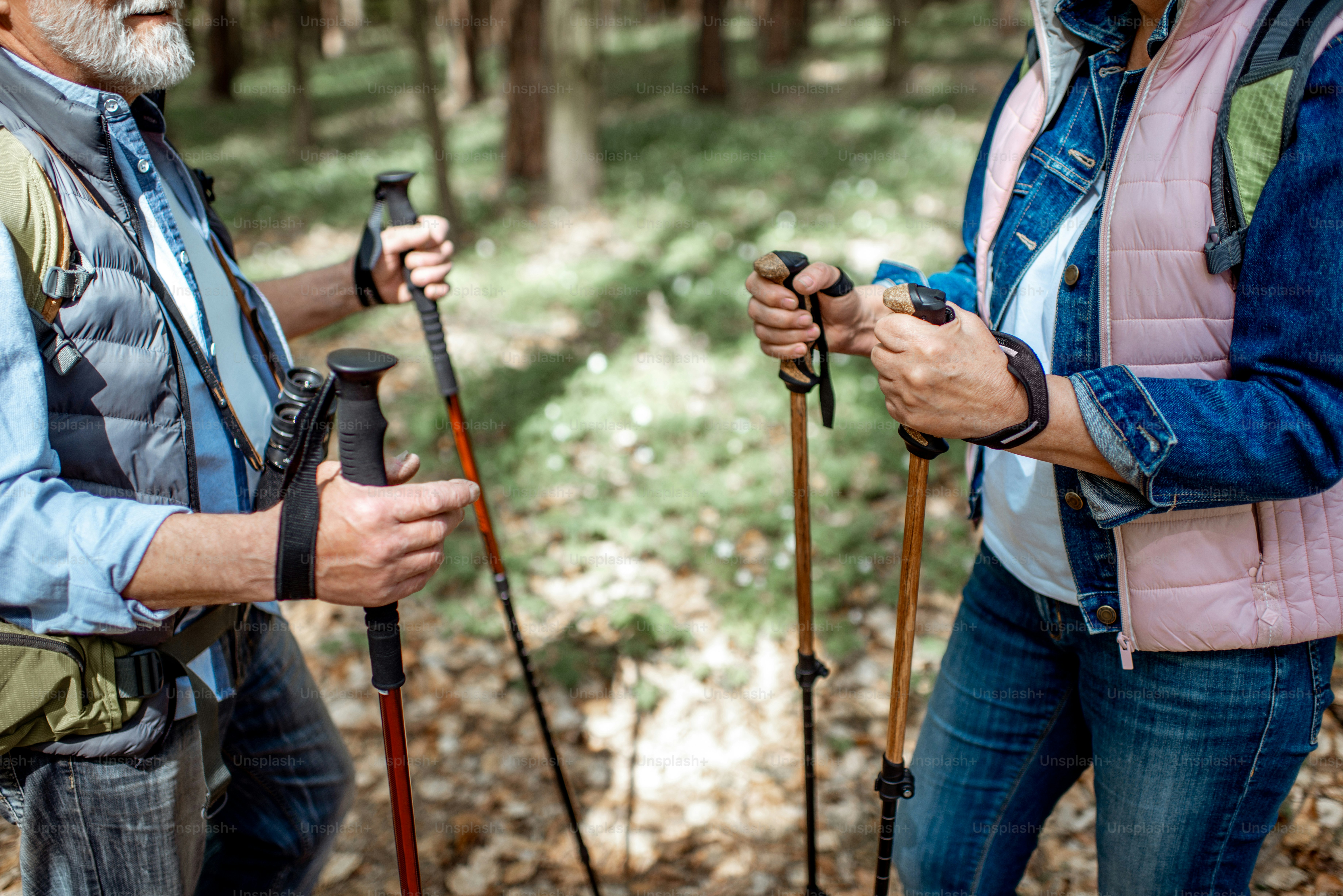 Älterer Mann und Frau wandern mit Trekkingstöcken im Wald, Nahaufnahme mit abgeschnittenem Gesicht