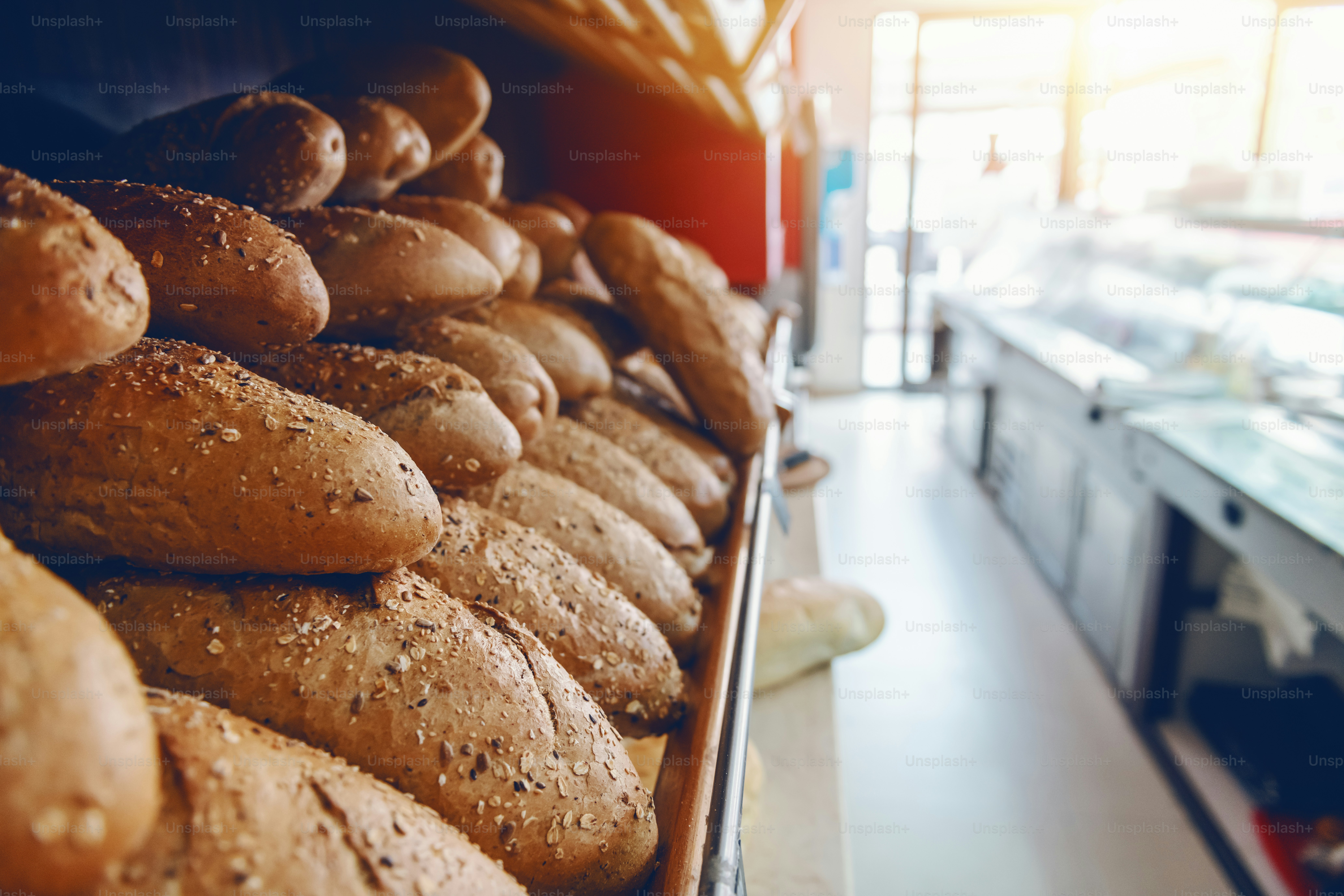 Deliziose pagnotte di pane fresche in fila su scaffali pronti per la vendita. Interno della panetteria.
