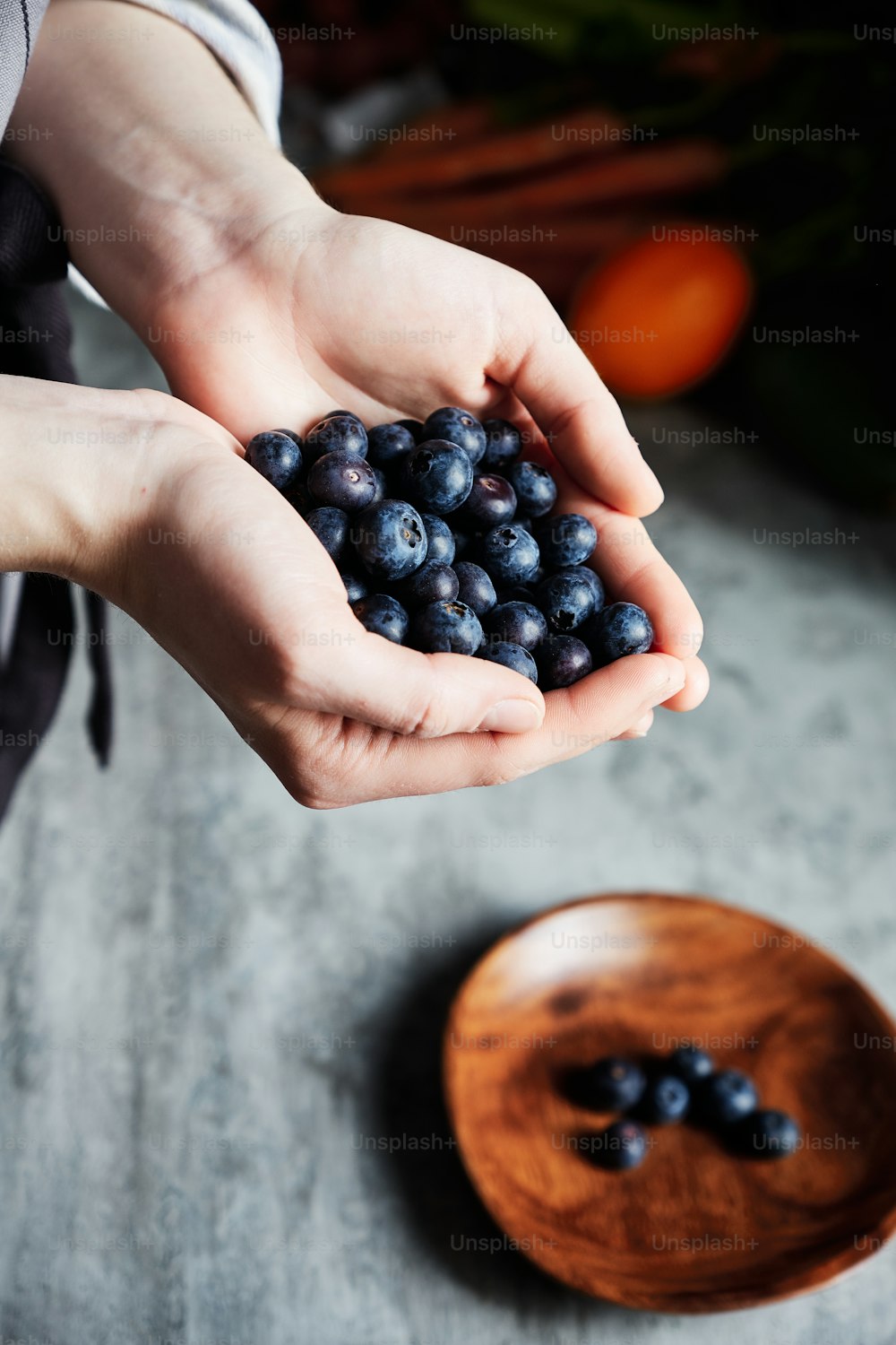Close up of female hands holding pile of fresh blueberries and pouring them onto plate