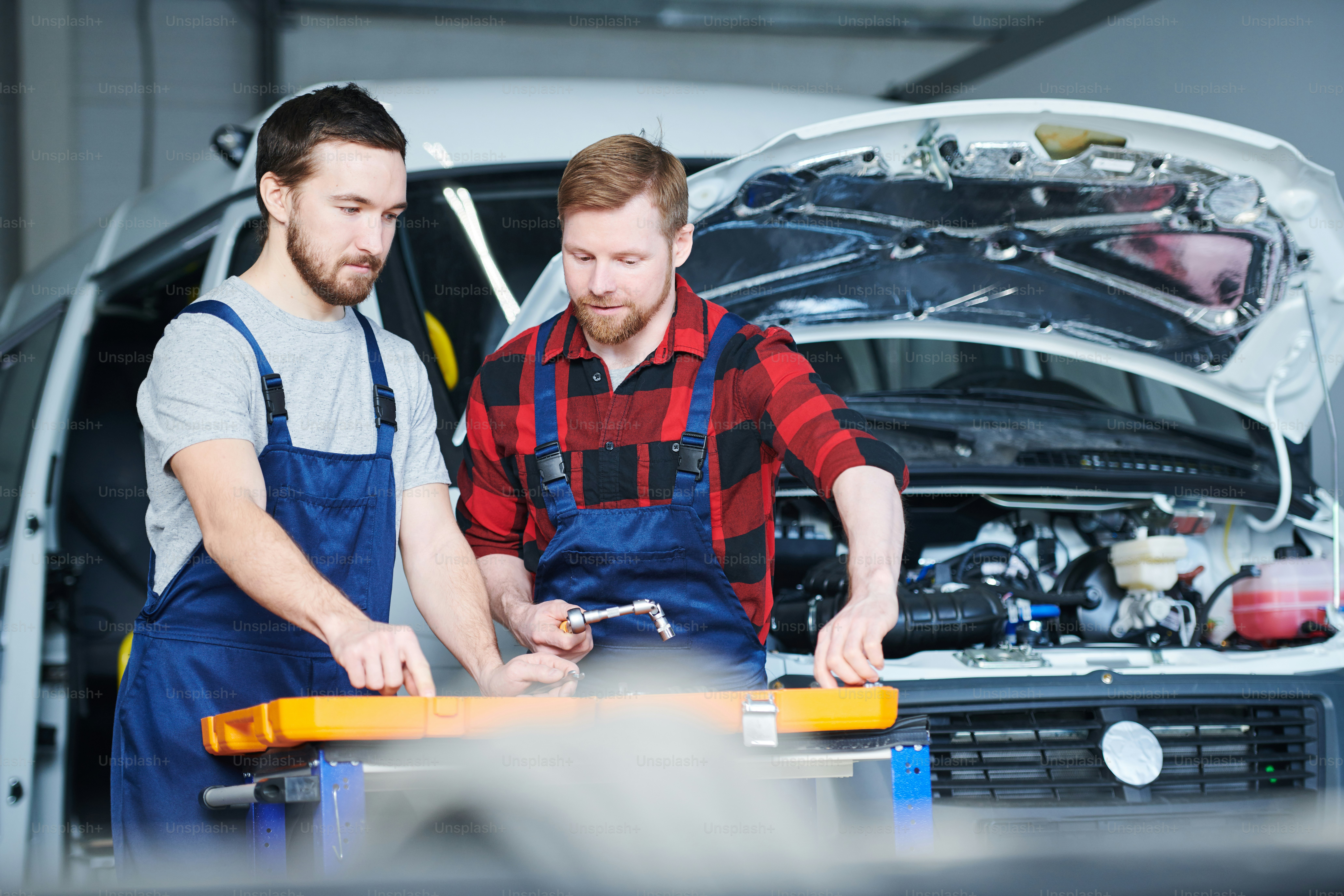 Two young professional maintenance engineers consulting while choosing handtools for repair work