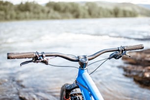 山の川の背景に自転車のハンドル。フリーライドとオフロードトレイルのコンセプト
