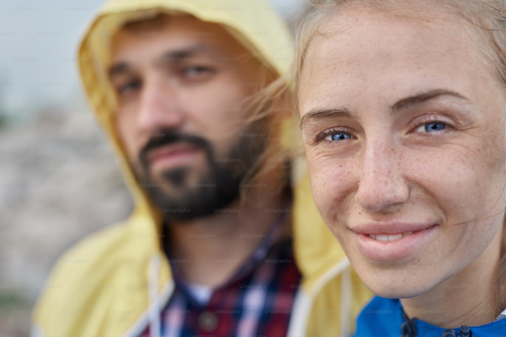 Close up face portrait of mid age couple outdoor, part of hiking series, they are wearing colorful jackets, summer time, full man face and part of woman face in selective focus