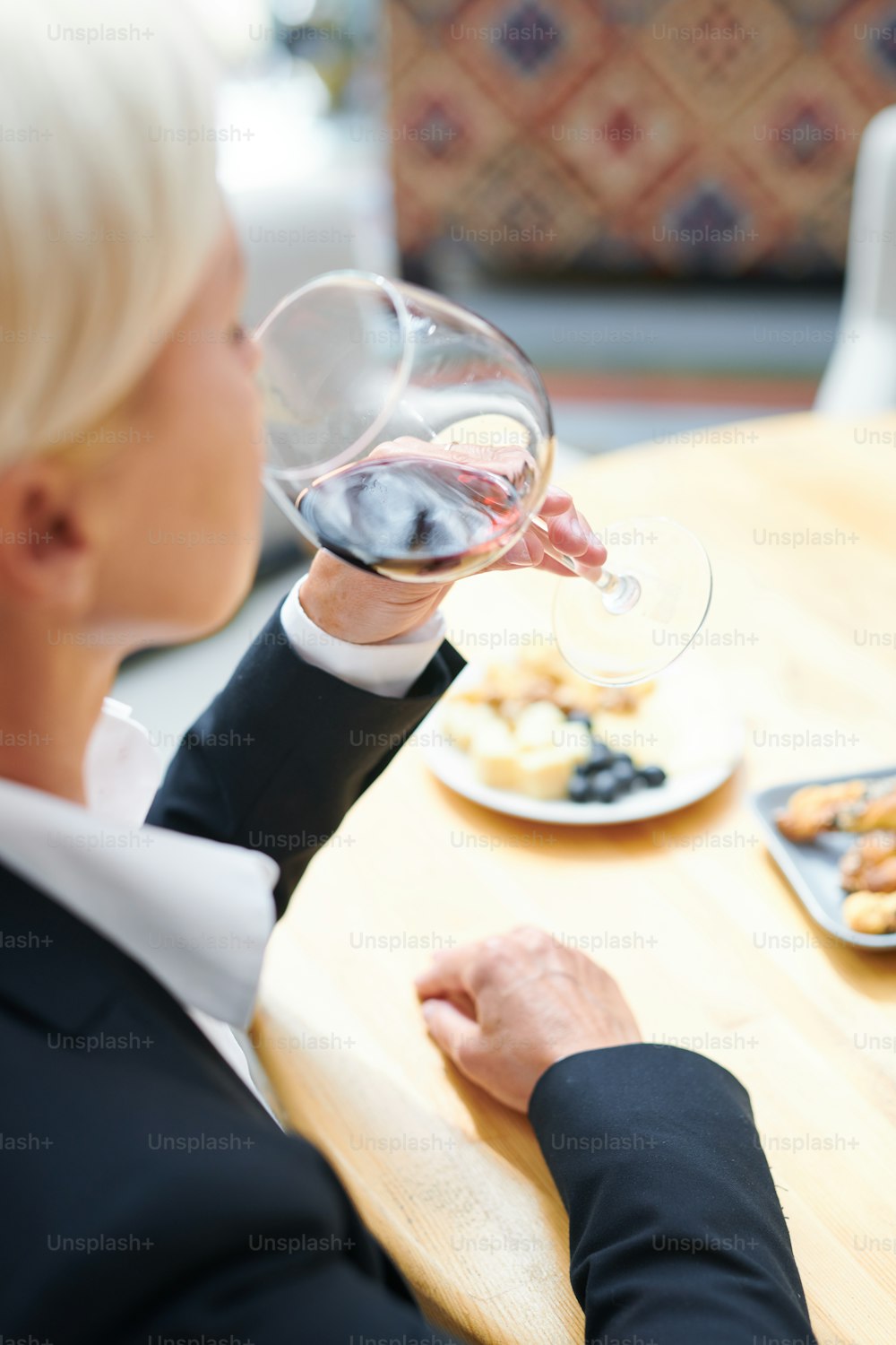 Professional mature female sommelier tasting red cabernet from wineglass while evaluating its flavor