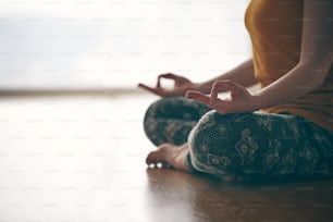 Close up in selective focus of female hands gesture mudra, while doing yoga vinyasa flow, Padmasana, nirvana state of mind