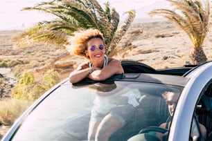 Travel summer holiday vacation concept with young caucasian cheerful people women couple traveling with convertible car together in friendship - tropical background and freedom lifestyle