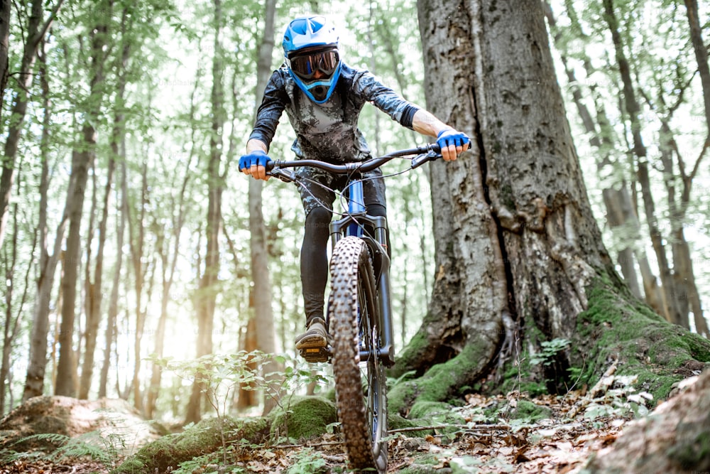 Professional well equipped cyclist riding downhill on the off road in the forest. Concept of an extreme sport and enduro cycling