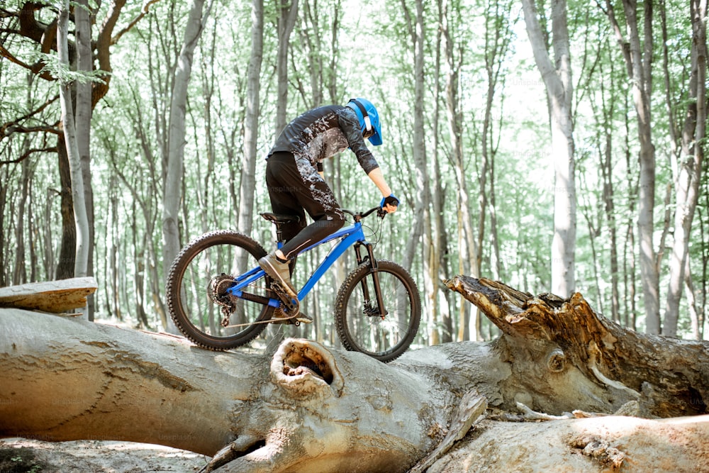 Professional well equipped cyclist riding downhill on the off road in the forest. Concept of an extreme sport and enduro cycling