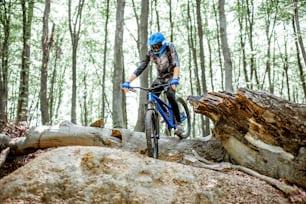 Professional well equipped cyclist riding downhill on the off road in the forest. Concept of an extreme sport and enduro cycling